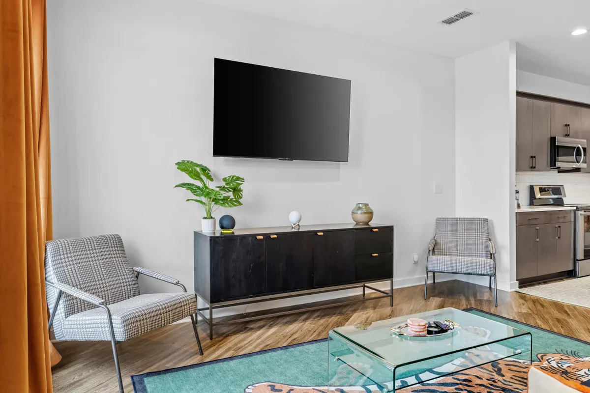 A comfortable living space centered around a flat-screen television, with a lush green plant and a modern coffee table. The area feels casual yet stylish, ideal for movie nights or quiet evenings in—activities highlighted as appealing for both couples and professionals.