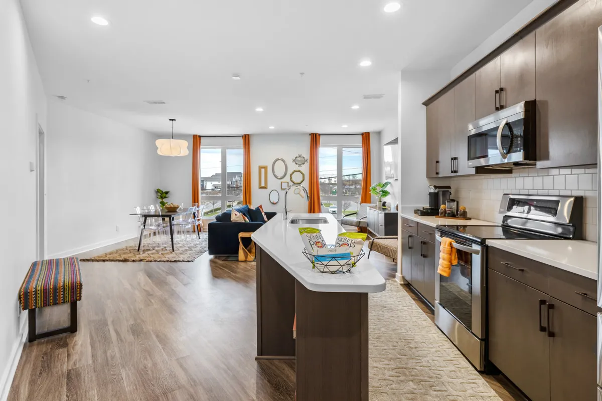 A spacious, light-filled interior with a kitchen island, dining table, and living room seating area framed by large windows. The open layout feels social and inviting, perfect for gathering with friends before heading out or winding down after exploring local hotspots.