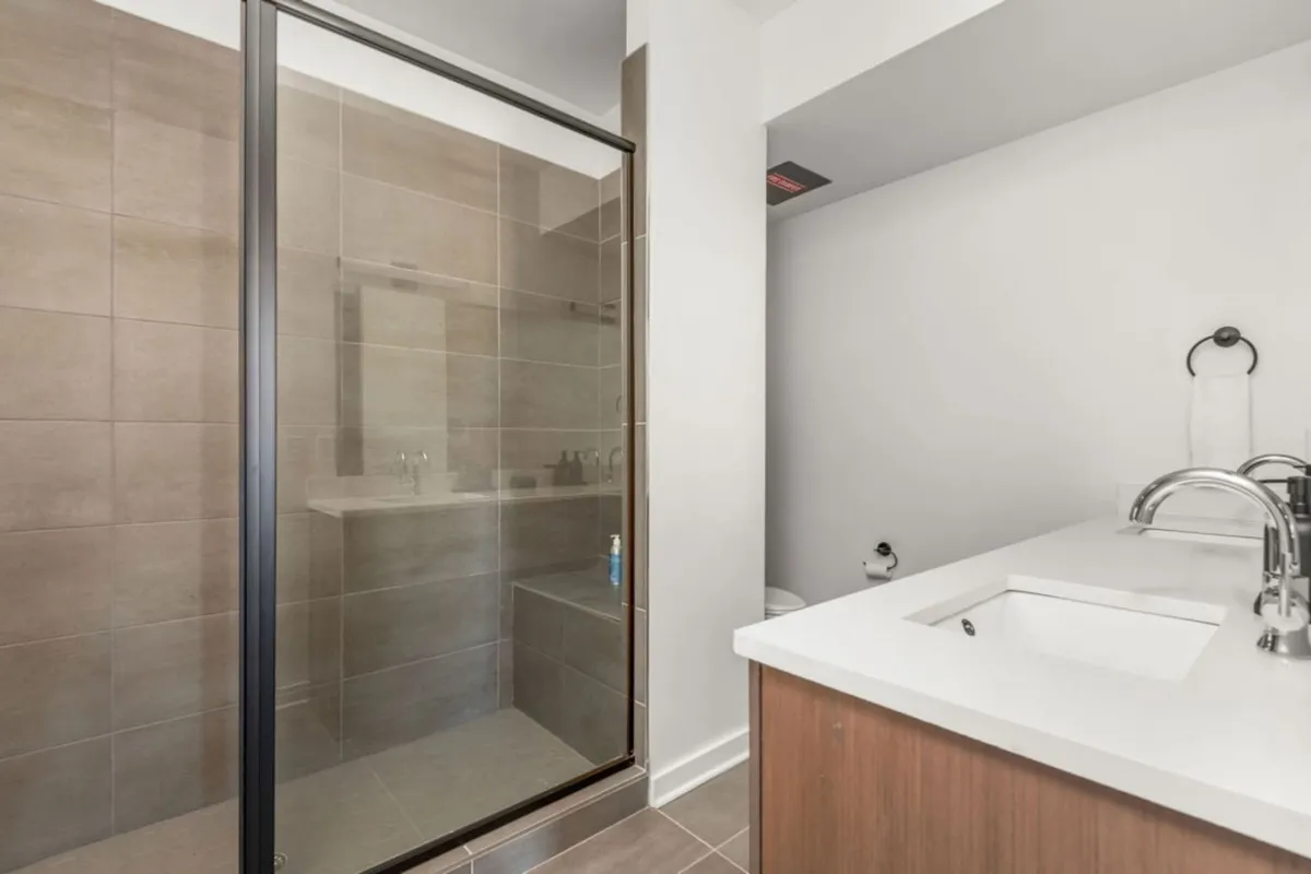 A contemporary bathroom with a glass shower enclosure, dual sink vanity, and textured tile walls. The space exudes freshness and tranquility, ideal for both energizing morning routines and relaxing evening rituals. The clean lines and calming palette enhance the sense of a private retreat.